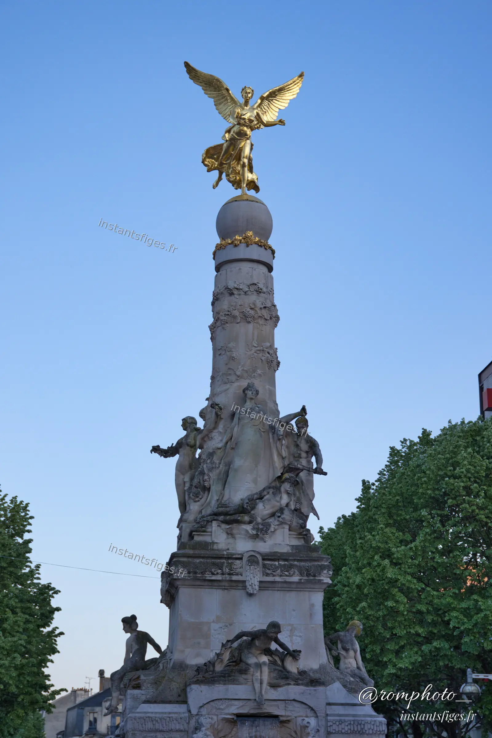 Statue dorée ailée au sommet d'une fontaine monumentale à Reims